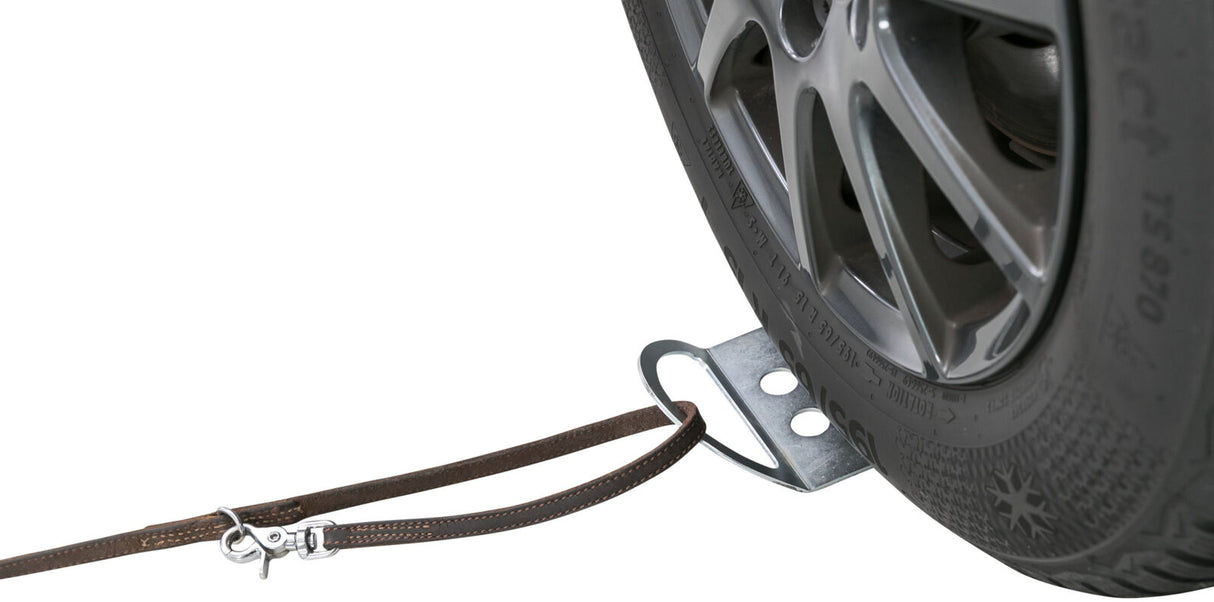 Nahaufnahme eines Autoreifens mit einem daran befestigten braunen Ledergurt über eine Metallhalterung.