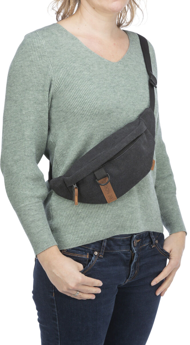 Person mit grünem Pullover trägt eine schwarze Bauchtasche, die quer über die Schulter hängt.