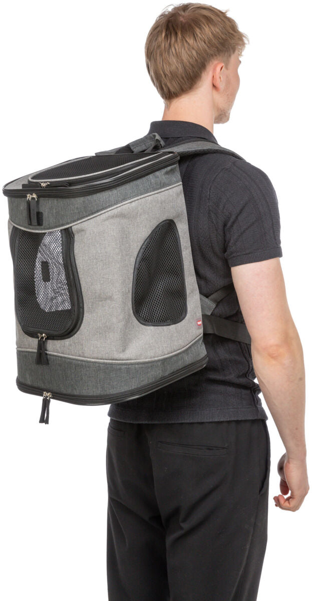 Grauer Rucksack mit schwarzen Netzfenstern und Reißverschlüssen, getragen von einer Person mit schwarzem Shirt.