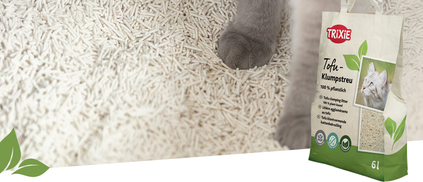 TRIXIE Tofu-Klumpstreu neben Katzenpfote auf pflanzlicher Einstreu, Verpackung mit Produktdetails im Vordergrund