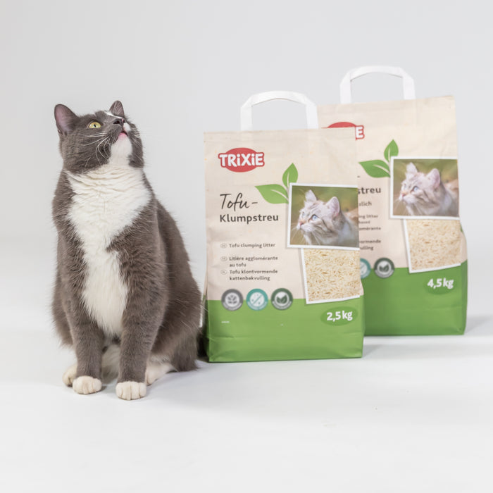 Katze neben TRIXIE Tofu Klumpstreu in 2,5 kg und 4,5 kg Verpackung vor hellem Hintergrund