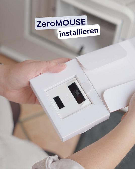 Foto von dem Gerät "ZeroMOUSE" welches in der Verpackung liegt und in der Hand gehalten wird. Im Hintergrund ist die Haustür zu sehen.