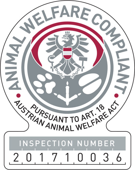 Das Bild zeigt ein rundes Emblem mit der Aufschrift "Animal Welfare Compliant", einem Adler in der Mitte und einer Prüfnummer unten.