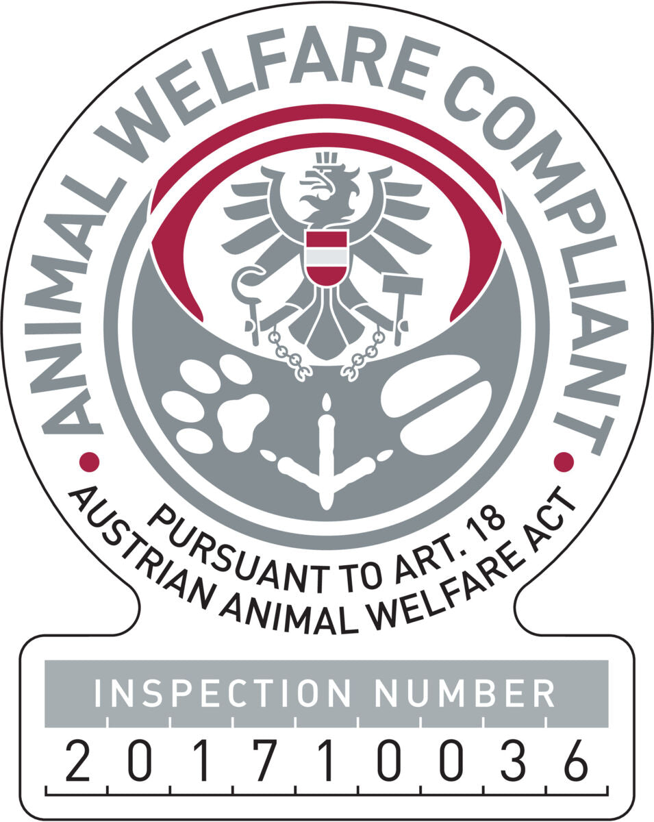 Das Bild zeigt ein rundes Emblem mit der Aufschrift "Animal Welfare Compliant", einem Adler in der Mitte und einer Prüfnummer unten.