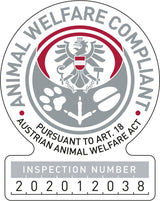 Graues und rotes Siegel mit Adler, Pfotenabdrücken, einer Kette und Text "Animal Welfare Compliant" sowie Prüfnummer 202012038.