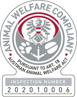Graues und rotes Abzeichen mit einem Adler und Text: "Animal Welfare Compliant, Pursuant to Art. 18 Austrian Animal Welfare Act, Inspection Number 2020100006".
