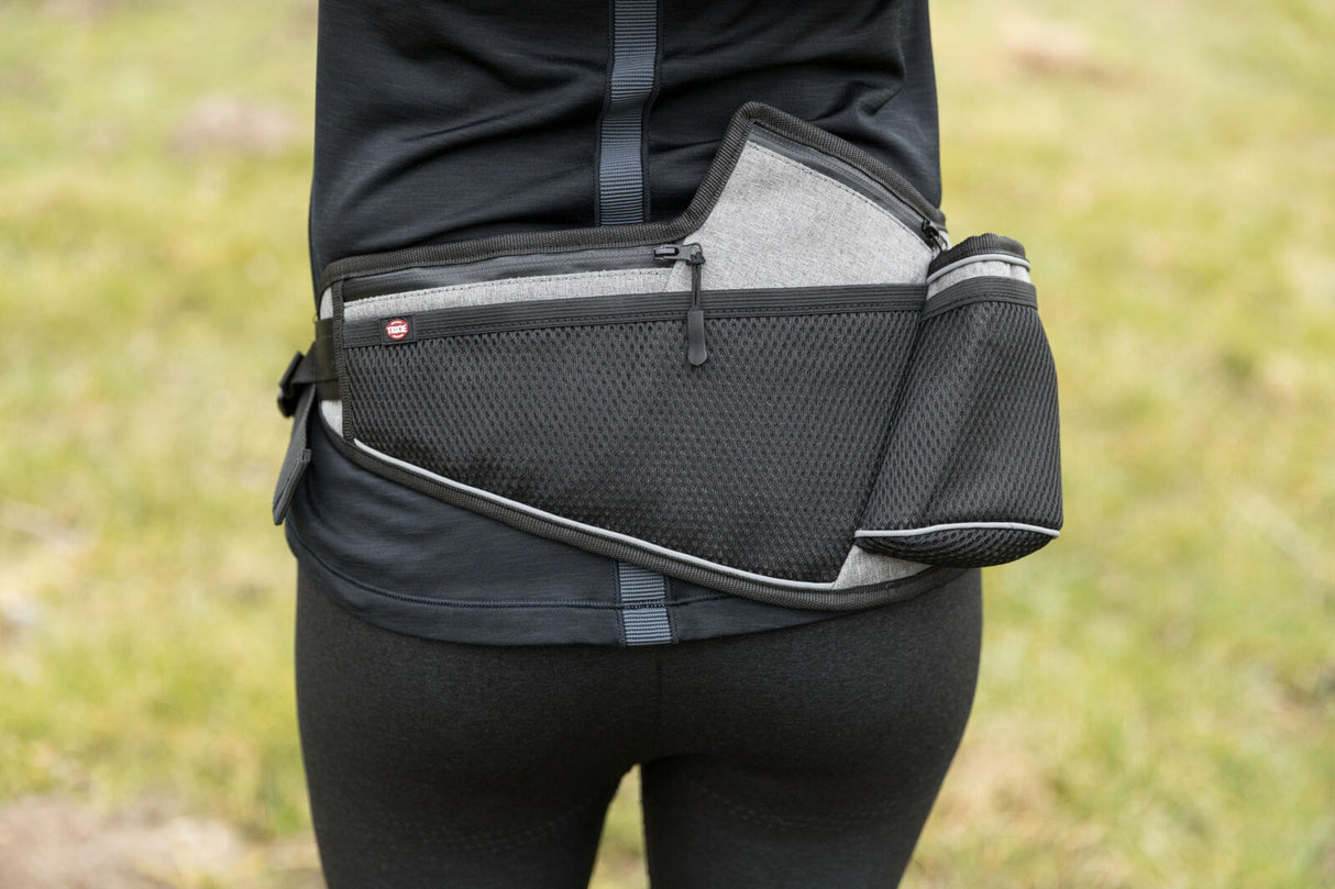 Person trägt einen schwarzen Hüftgurt mit mehreren Taschen im Freien.