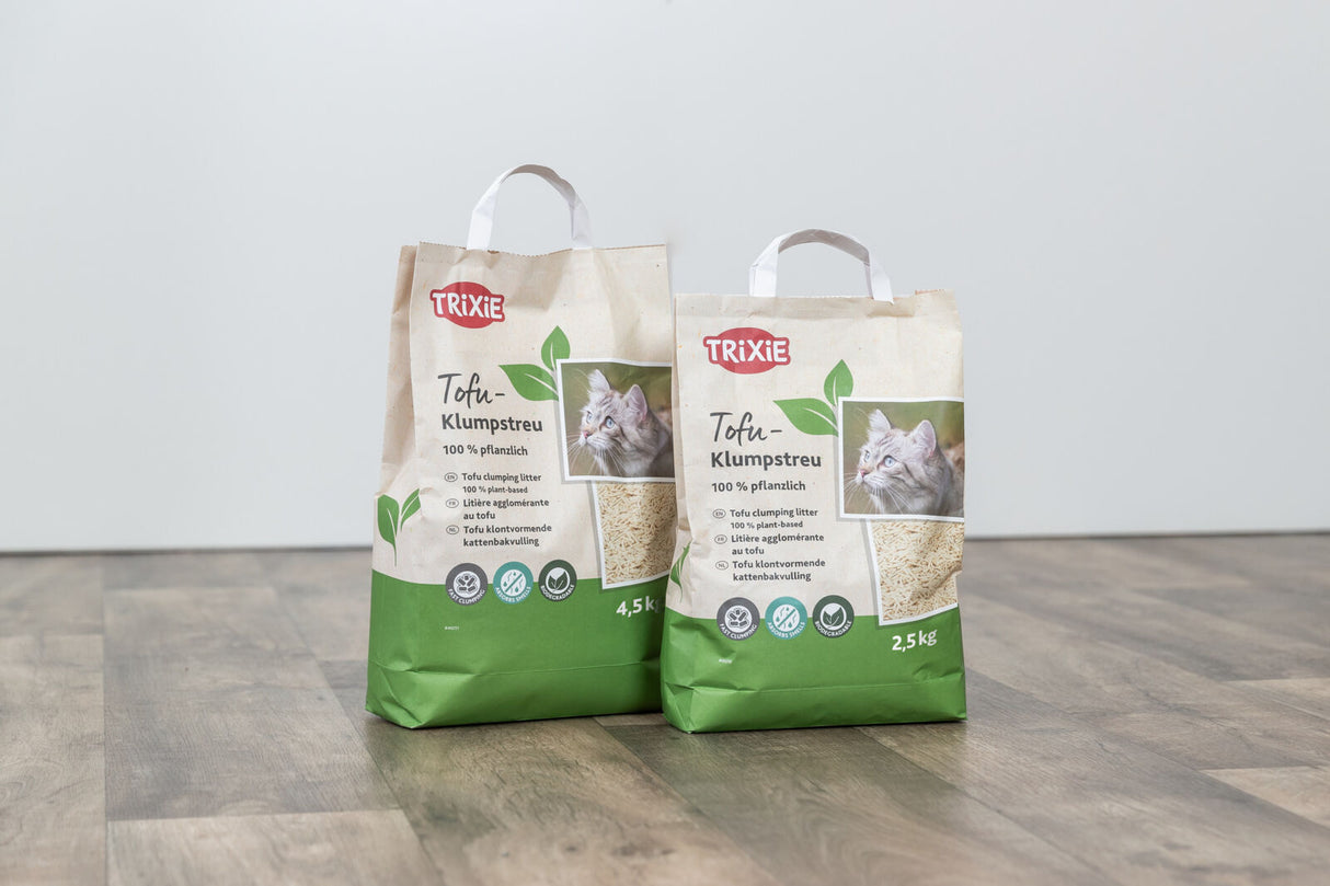 Zwei Packungen TRIXIE Tofu-Klumpstreu mit Katzenmotiv auf Holzboden.