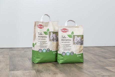 Zwei Packungen TRIXIE Tofu-Klumpstreu mit Katzenmotiv auf Holzboden.