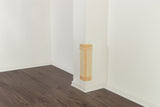 Helles Zimmer mit weißer Wand und dunklem Holzboden, ein beigefarbener Kratzschutz ist an der Ecke der Wand angebracht.