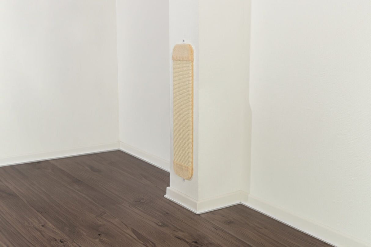 Kratzbrett mit beigem Rahmen an weißer Wand in einer Zimmerecke mit dunklem Holzboden.