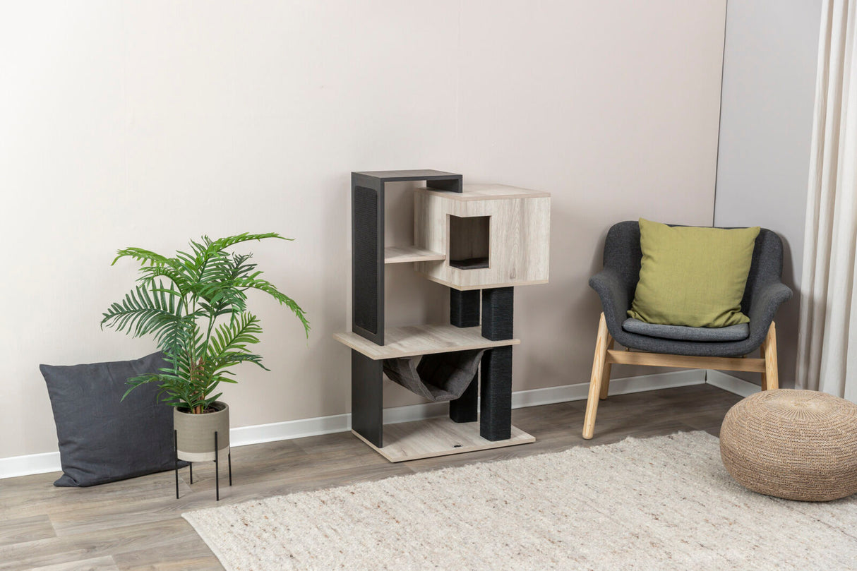 Ein Holzkatzenbaum mit mehreren Ebenen steht neben einem grauen Sessel mit grünem Kissen und einer Pflanze.