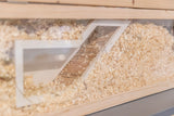 Holzterrarium mit Einstreu gefüllt, eine Glastür zeigt eine schräg verlaufende Holzleiter innen.