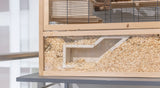 Holzgehege mit Gitter, teilweise gefüllt mit Holzspänen, auf einer grauen Oberfläche stehend.