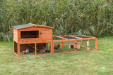 Holzstall mit Gitter für Kleintiere auf einer Rasenfläche, innen zwei Kaninchen mit kleinem Unterstand und Tunnel.