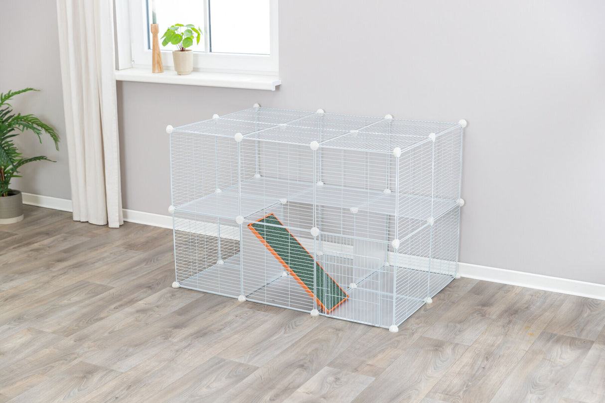 Großer weißer Metallkäfig mit mehreren Ebenen und Rampe in einem Zimmer mit grauem Boden und Pflanzen.