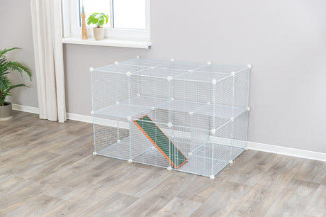 Großer weißer Metallkäfig mit mehreren Ebenen und Rampe in einem Zimmer mit grauem Boden und Pflanzen.