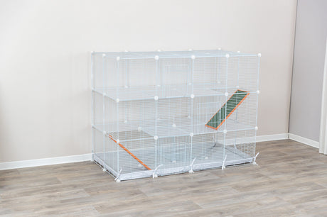 Weiße, mehrstöckige Gitterkonstruktion mit Rampen auf Holzfußboden vor einer hellen Wand.