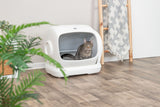 Getigerte Katze sitzt in einer weißen Katzentoilette mit Haube auf Holzboden.