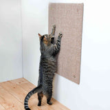 Eine Katze kratzt an einer vertikalen Kratzmatte aus Sisal, die an einer weißen Wand befestigt ist.