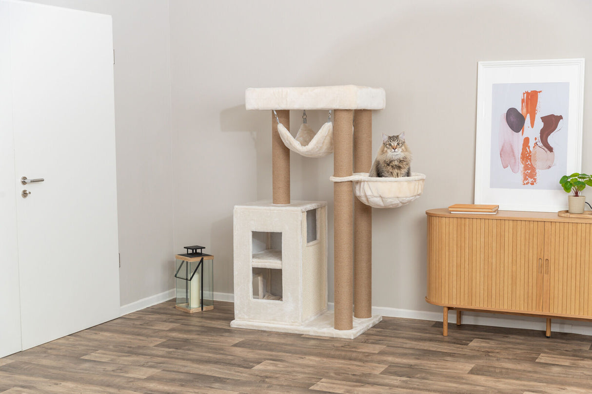 Kratzbaum mit Plüsch und Sisalsäulen, darin sitzende Katze, daneben helle Wand, Tür, Holzkommode und Bild.