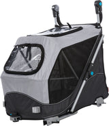 Grau-schwarzer Fahrradanhänger mit Netzfenstern und Metallrahmen, Rückenstützen oben; sichtbar sind Halterungen und Griffe.