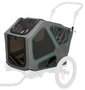 Grau-schwarzer Fahrradanhänger mit transparenten Fenstern und grünem Rahmen, neben großen Rädern.