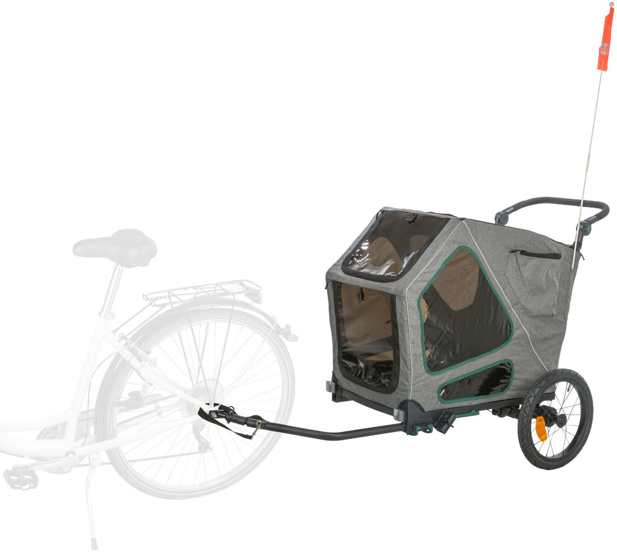 Grauer Fahrradanhänger mit zwei Rädern, klarem Fenster, oranger Fahne und Anhängerkupplung an einem Fahrrad befestigt.