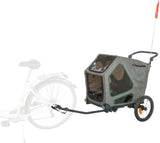 Grauer Fahrradanhänger mit zwei Rädern, klarem Fenster, oranger Fahne und Anhängerkupplung an einem Fahrrad befestigt.