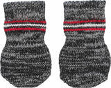 Zwei gestrickte Socken in Schwarz, Weiß und Rot mit roten und weißen Streifen auf grauem Hintergrund.
