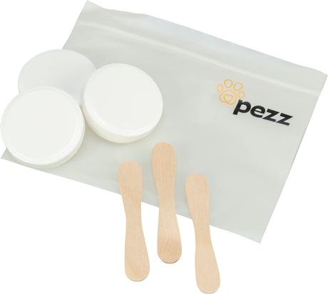 Drei weiße Dosen, drei Holzspatel und eine durchsichtige Tasche mit "pezz"-Logo.