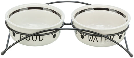 Zwei weiße Futternäpfe mit schwarzer Beschriftung "FOOD" und "WATER" auf Metallständer mit Pfotenmotiv.