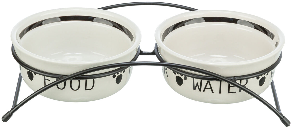 Zwei weiße Futternäpfe mit schwarzer Beschriftung "FOOD" und "WATER" auf Metallständer mit Pfotenmotiv.