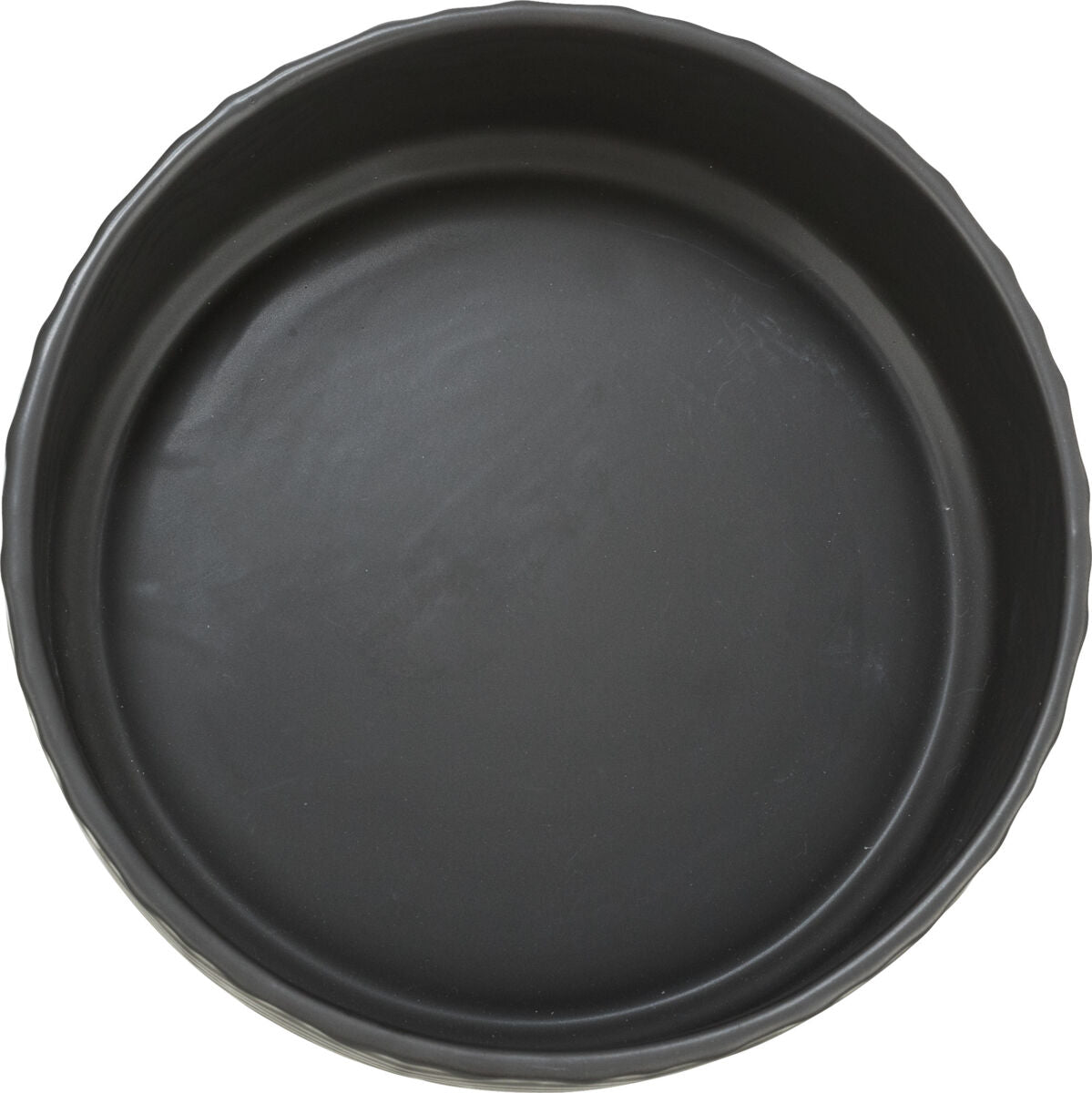 Runde schwarze Backform mit gewelltem Rand, von oben fotografiert.