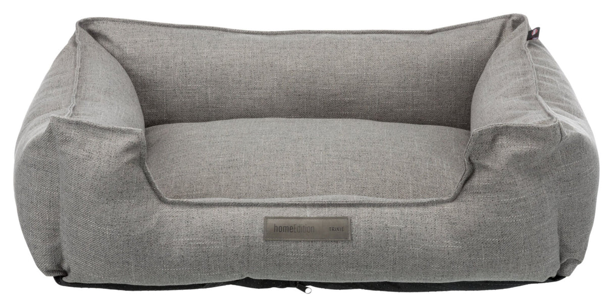 Graues Haustierbett in rechteckiger Sofaform mit erhöhtem Rand und einem Etikett "homeEdition Trixie".