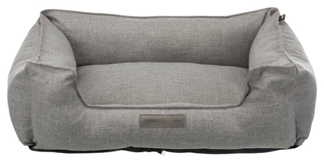 Graues Haustierbett in rechteckiger Sofaform mit erhöhtem Rand und einem Etikett "homeEdition Trixie".
