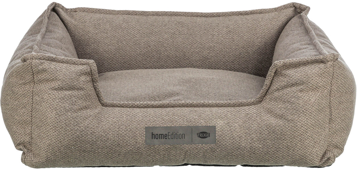 Kissenförmiges, beigefarbenes Hundebett mit stehendem Rand und Etikett „homeEdition TRIXIE“.