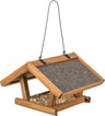 Holz-Vogelfutterhaus mit spitzem Dach, bedeckt mit dunklem Material, hängend an Metallhaken, gefüllt mit Samen.