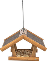 Vogelfutterhaus aus Holz mit Satteldach, Schindeln und Metallaufhängung, gefüllt mit verschiedenen Körnern.