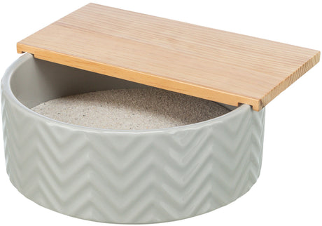 Rundes graues Gefäß mit Zickzack-Muster, gefüllt mit Sand und teils abgedeckt durch einen Holzdeckel.