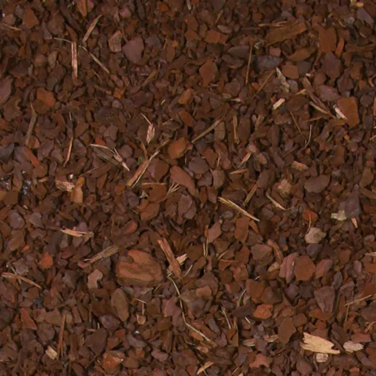 Braune Holzchips mit unregelmäßigen Formen bedecken die Oberfläche vollständig.