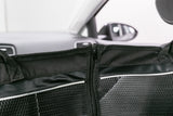 Schwarzes Trennnetz mit Reißverschluss in einem Auto, Hintergrund zeigt verschwommene Autoinnenteile.