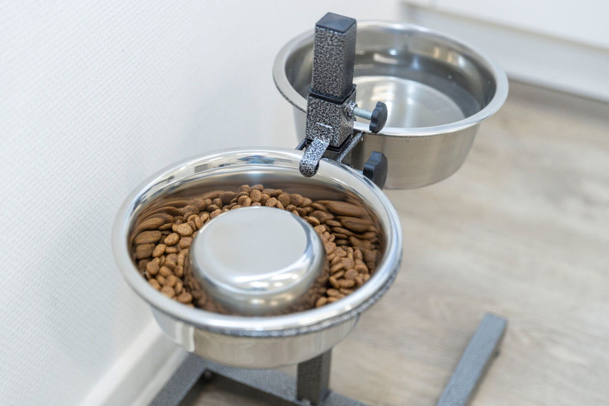 Zwei Edelstahlnäpfe auf einem Ständer, einer mit Trockenfutter, der andere mit Wasser gefüllt.