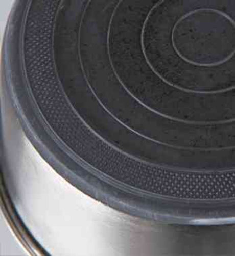 Unterseite eines Kochtopfs mit kreisförmigem Muster auf schwarzem Hintergrund.