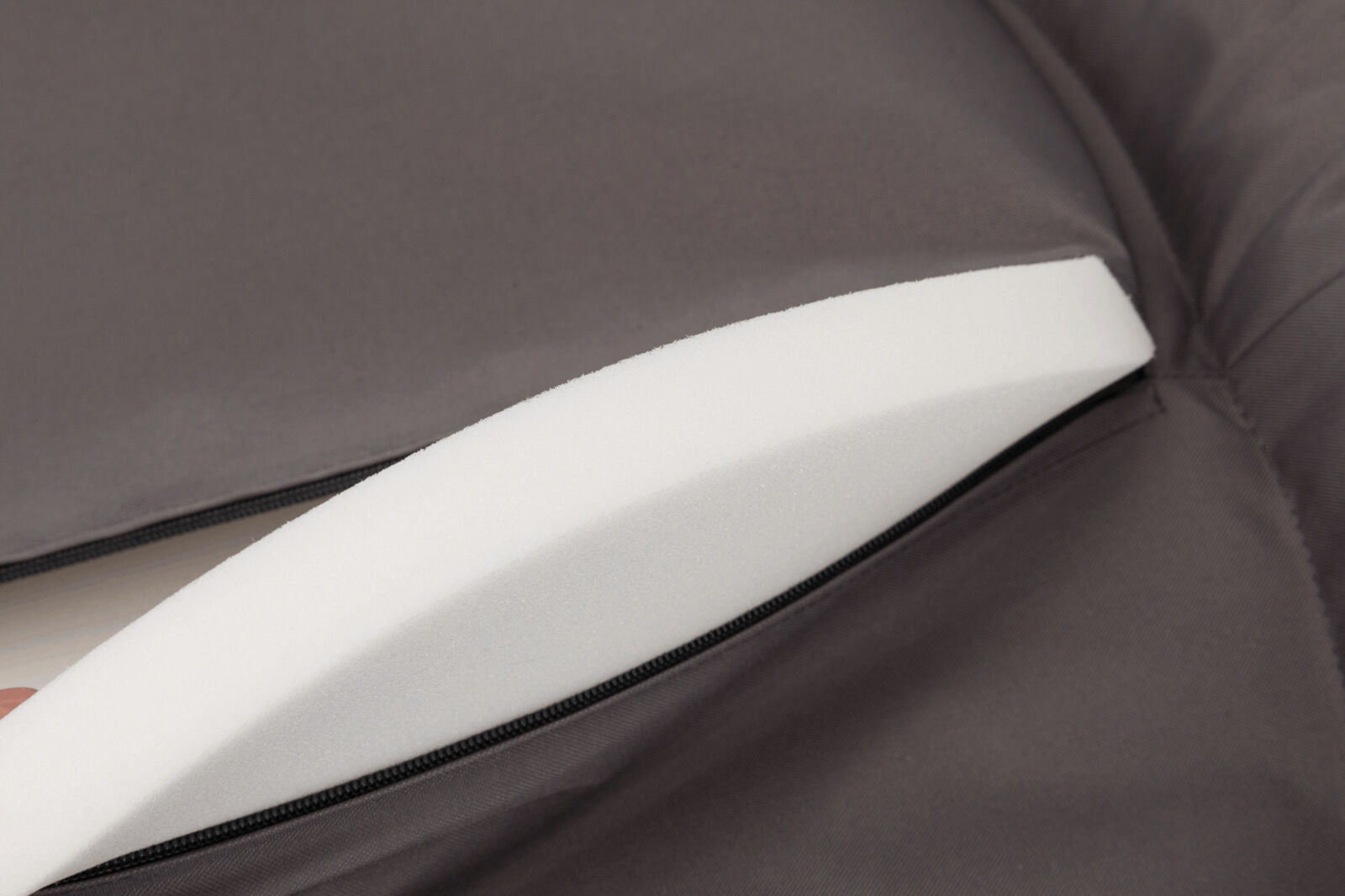 Nahaufnahme eines weißen Schaumstoffs, der teilweise in einer dunkelgrauen Tasche mit Reißverschluss steckt.