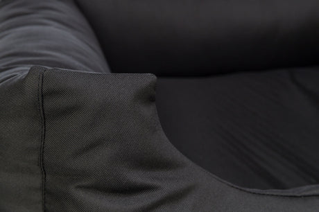 Ein Detail eines schwarzen Stoffbezugs mit texturierter Oberfläche und weichen Falten an der Ecke.