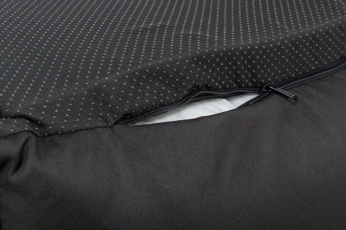 Nahaufnahme eines schwarzen Stoffes mit Punktmuster, ein Reißverschluss ist teilweise geöffnet und darunter ist weißes Material sichtbar.