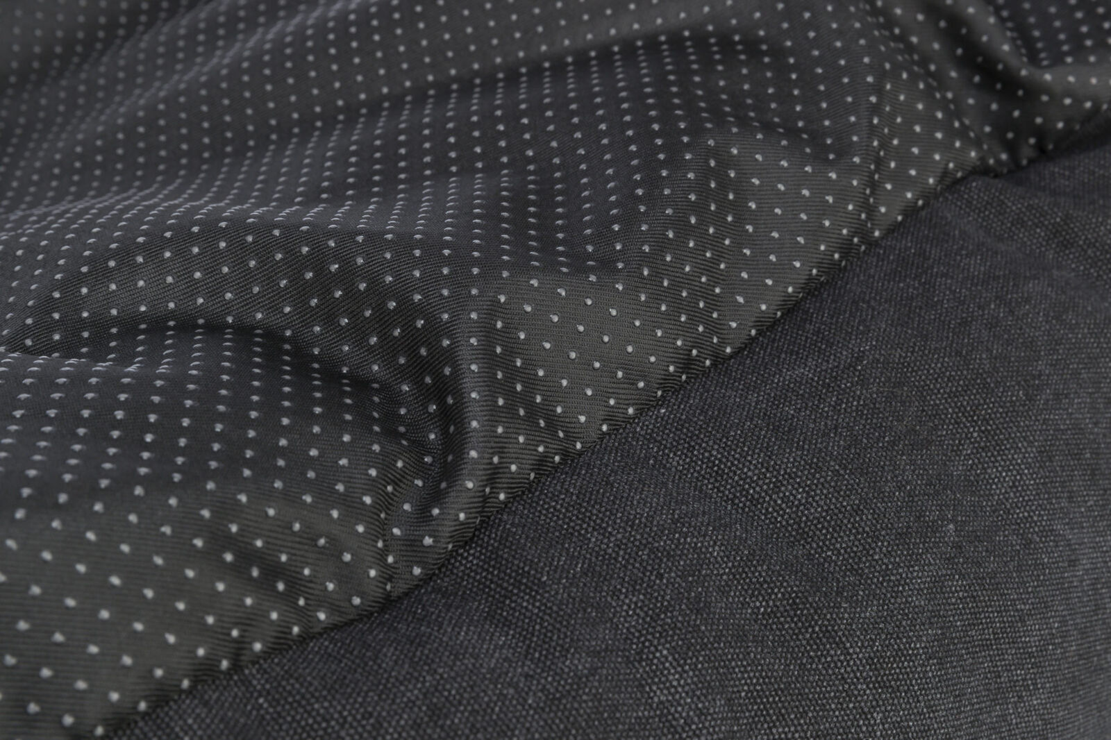 Schwarzer Stoff mit kleinen, weißen Punkten, daneben ein einfarbiger schwarzer, texturierter Bereich.