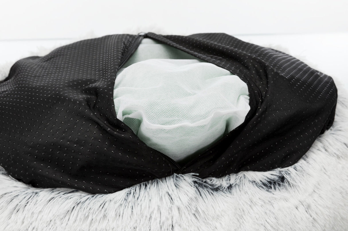 Schwarzer Stoff mit Punkten, darunter weißes Netzmaterial, auf grauem, flauschigem Hintergrund sichtbar.