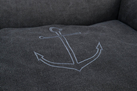 Graue Stoffoberfläche mit einem eingestickten, blauen Ankerdesign auf der Sitzfläche.